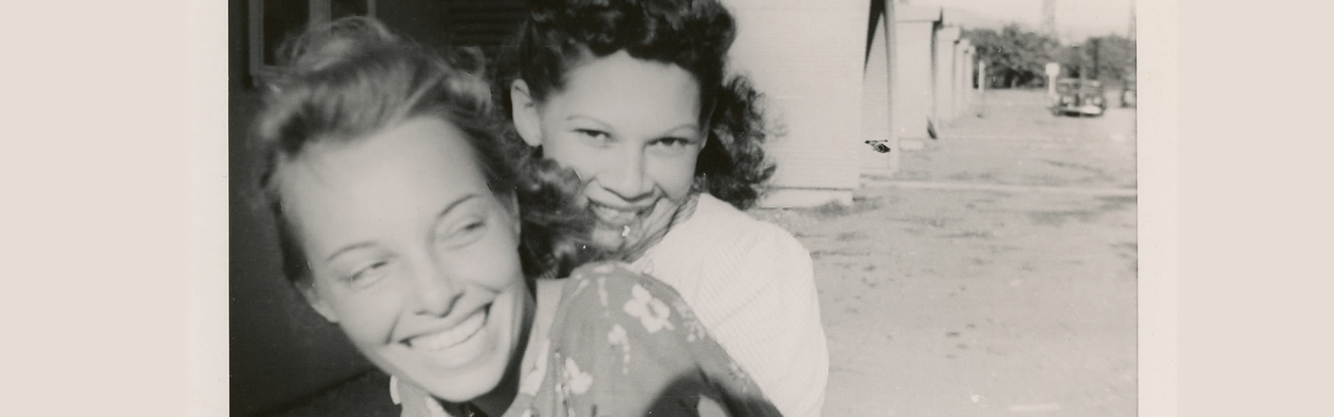 Two girls riding a bicycle in front of the Quonset Huts in Post-War Whittier